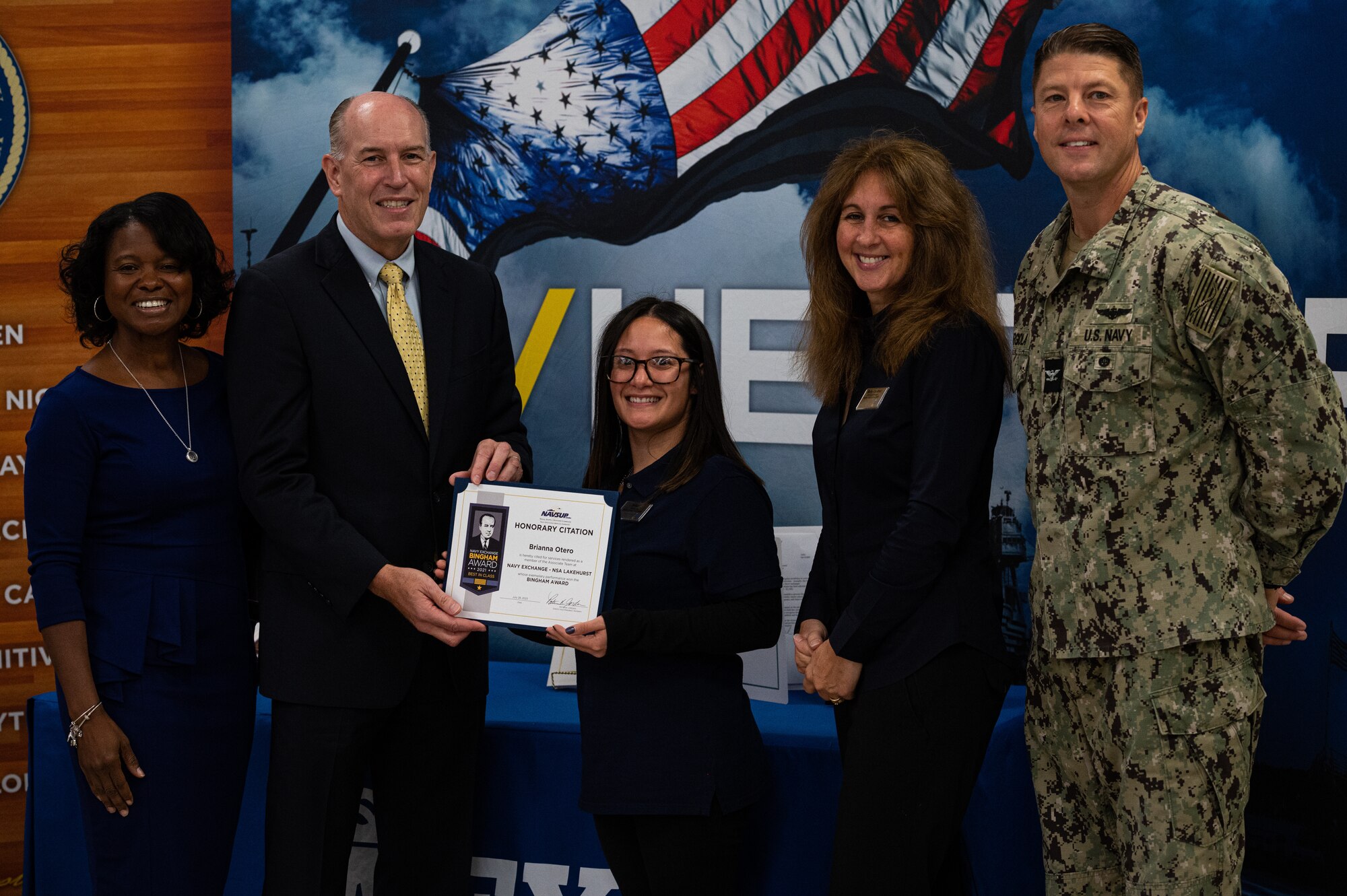 Christopher Burns, Navy Exchange Service Command senior vice president, presents Brianna Otero, Navy Exchange Lakehurst associate, the 2021 Bingham Award at Joint Base McGuire-Dix-Lakehurst, N.J., Oct. 18, 2022.