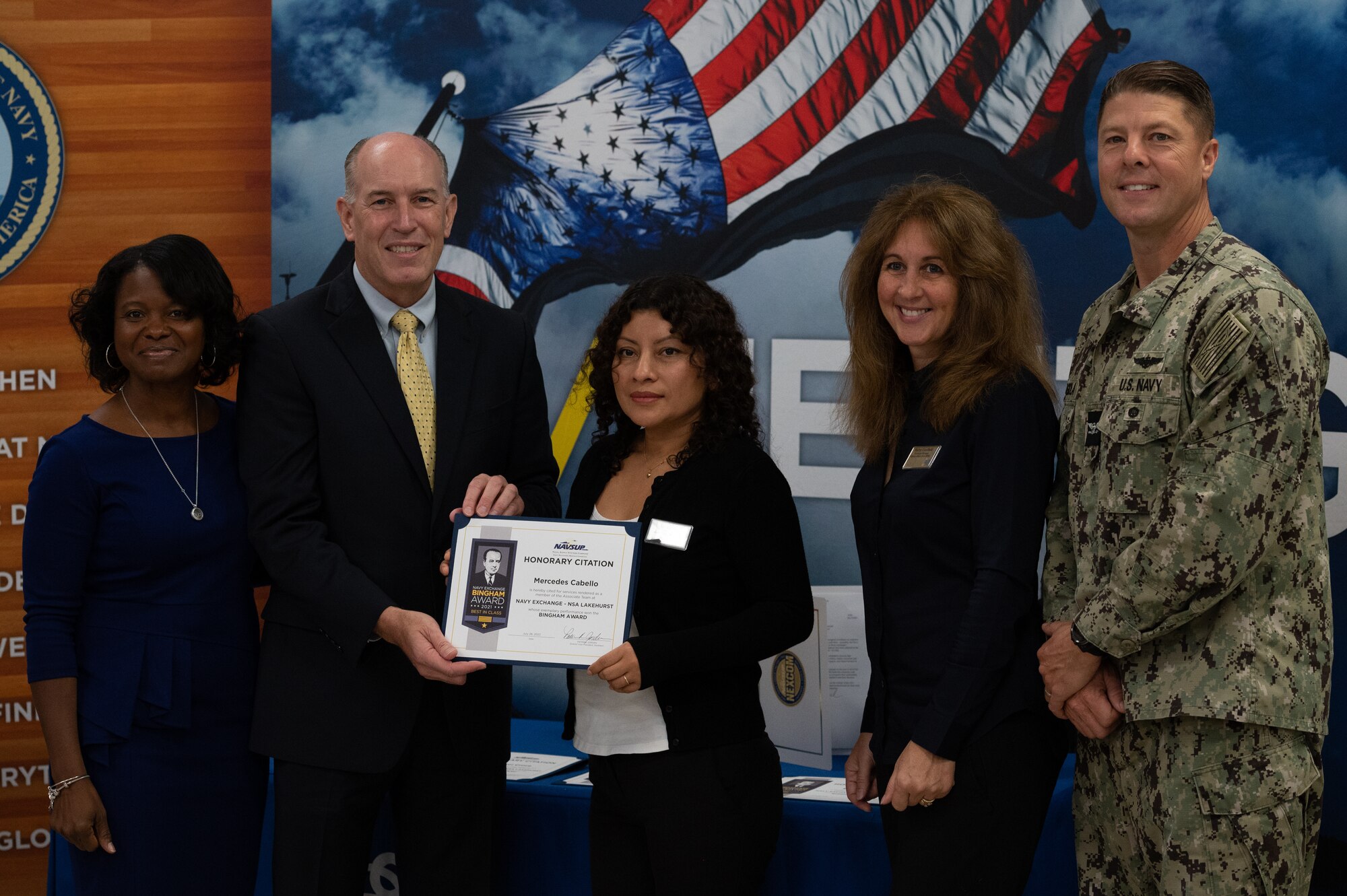 Christopher Burns, Navy Exchange Service Command senior vice president, presents Mercedes Cabello, Navy Exchange Lakehurst associate, the 2021 Bingham Award at Joint Base McGuire-Dix-Lakehurst, N.J., Oct. 18, 2022.