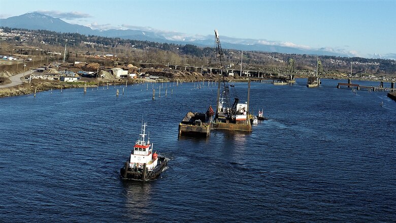 A tugboat is returning the barge and leaving the area along the Snohomish River.