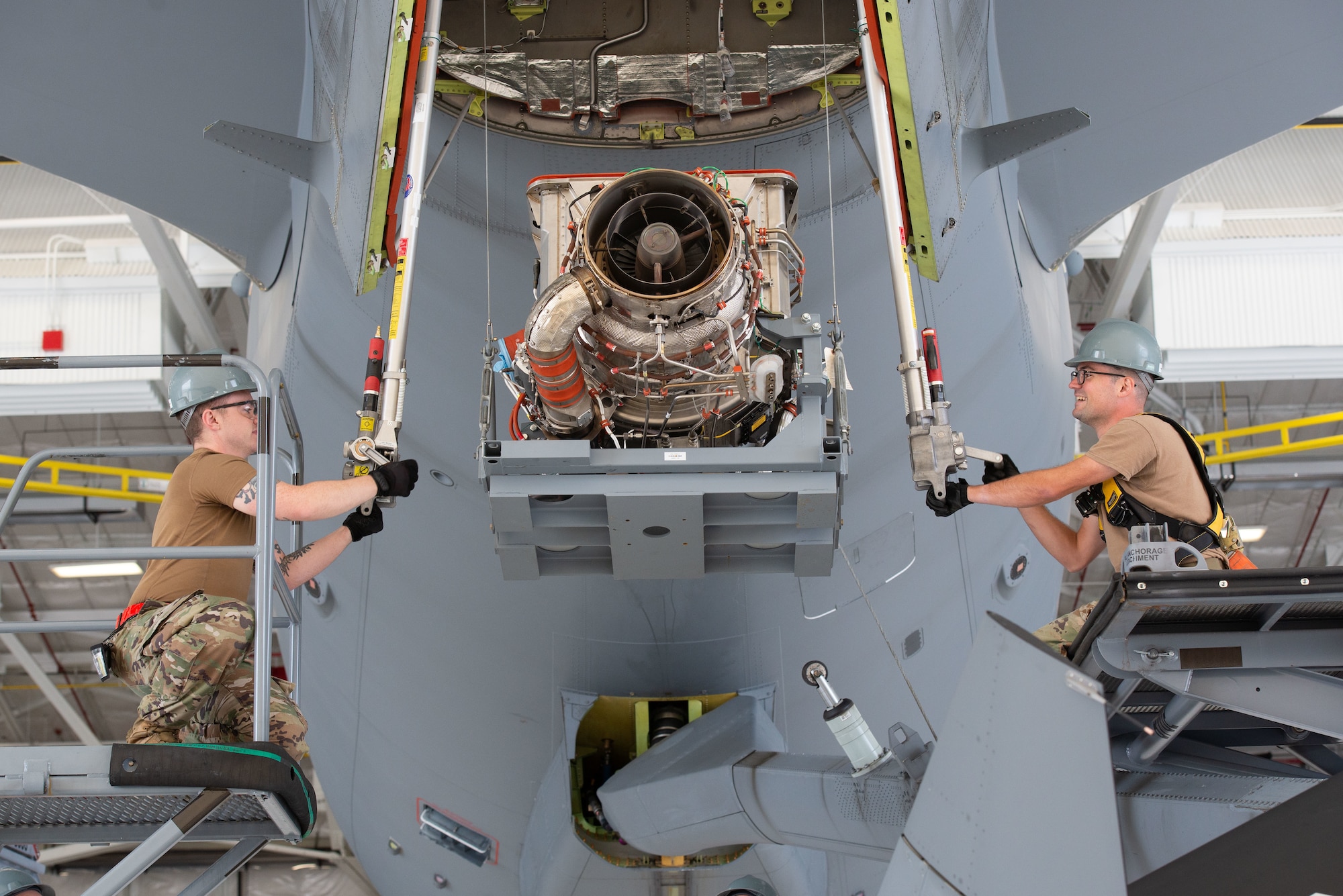 Mechanics hoist engine into aircraft