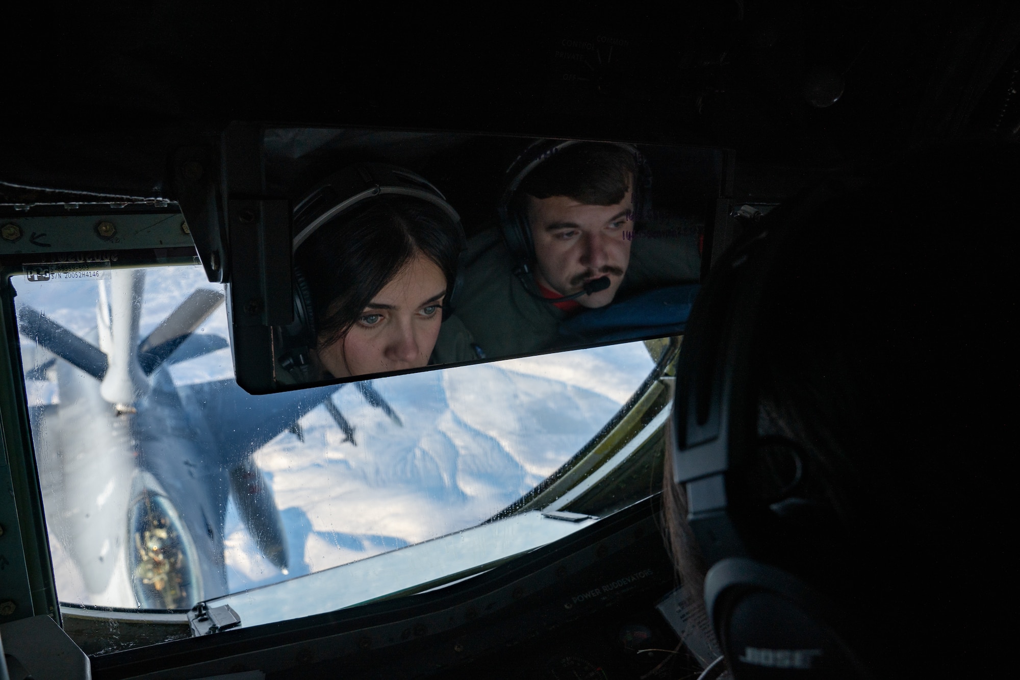People in mirror refueling a plane