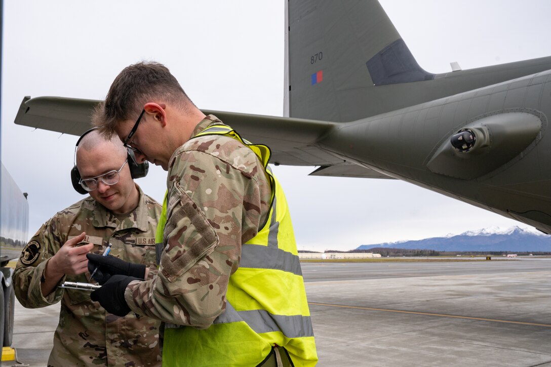 U.S. Air Force Airman 1st Class Mikhail Topaland British Royal Air Force Air Specialist (Class 1) Technician Alex Parker fill out paperwork.
