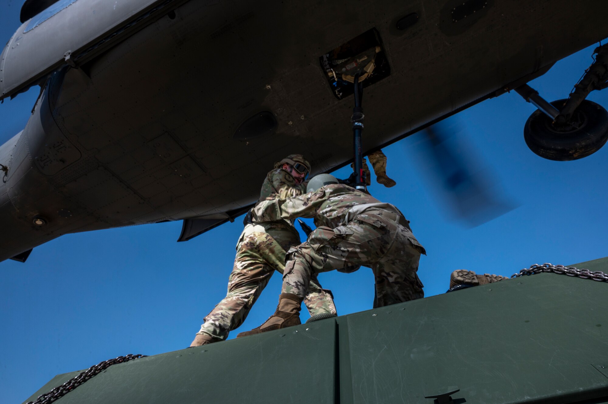 U.S. Air Force Staff Sgts. Miles Euro, 51st Munitions Squadron munitions operations supervisor, and Shelbie Morris, aerospace ground equipment technician, secures cargo to a U.S. Army Black Hawk helicopter during an integrated sling load training at Osan Air Base, Oct. 13, 2022.