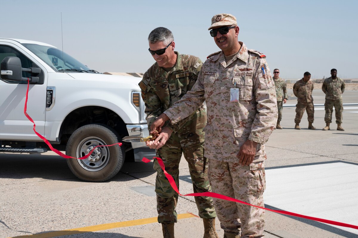 U.S. Air Force Col. George Buch Jr., 386th Air Expeditionary Wing commander, and Kuwait Air Force Brig. Gen. Murbarke Al-Qahtani, Ali Al Salem Air Base commander, cut a ribbon together during the ribbon cutting ceremony for the reopening of the South runway and taxiway at Ali Al Salem Air Base, Kuwait, October 13, 2022. With the runway construction completed, the runway will enable future mission success for years to come and is symbolic of the fruits of joint and coalition teamwork. This image was altered to remove a security item. (U.S. Air Force photo by Staff Sgt. Dalton Williams)