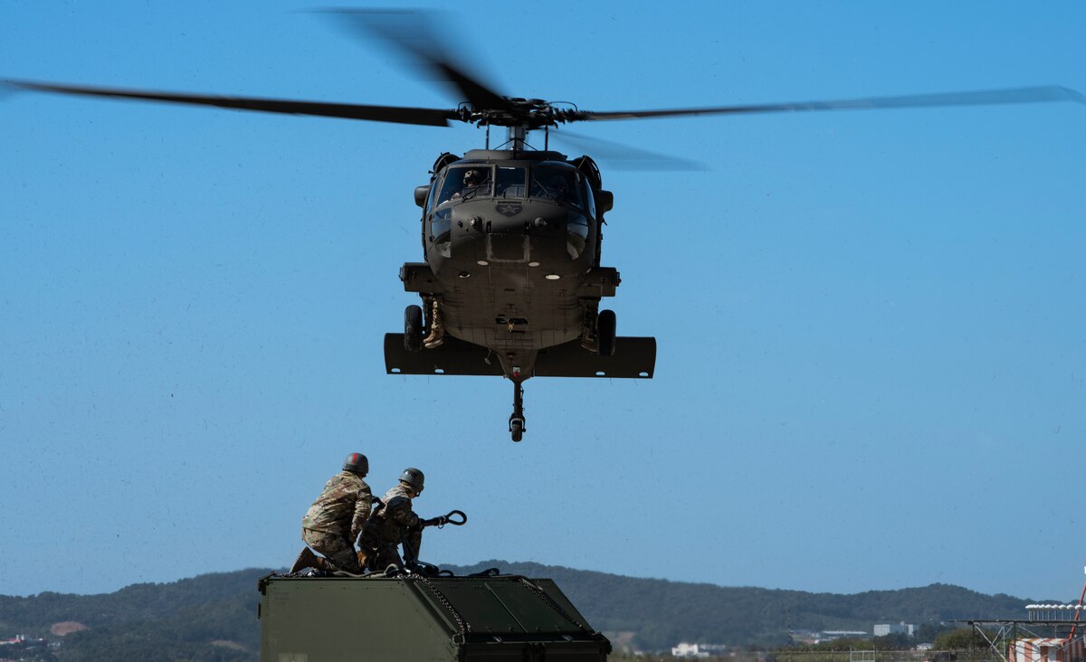 Senior Airmen Giancarlo Hernandez and John Millan-Irizarry, 51st Maintenance Squadron aerospace ground equipment journeymen, wait to secure an Internal Slingable Unit to a U.S. Army Black Hawk helicopter during an integrated sling load training at Osan Air Base, Republic of Korea, Oct. 13, 2022.