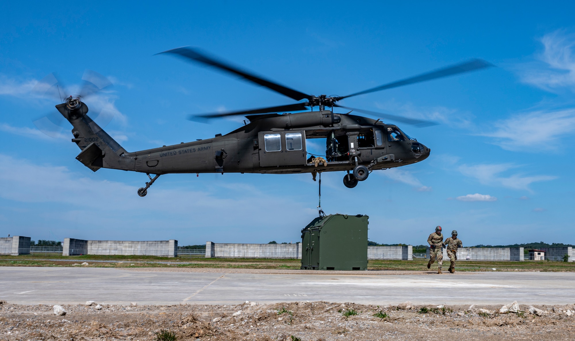 Senior Airmen Giancarlo Hernandez and John Millan-Irizarry, 51st Maintenance Squadron aerospace ground equipment journeymen, run after securing an Internal Slingable Unit to a U.S. Army Black Hawk helicopter during an integrated sling load training at Osan Air Base, Republic of Korea, Oct. 13, 2022.