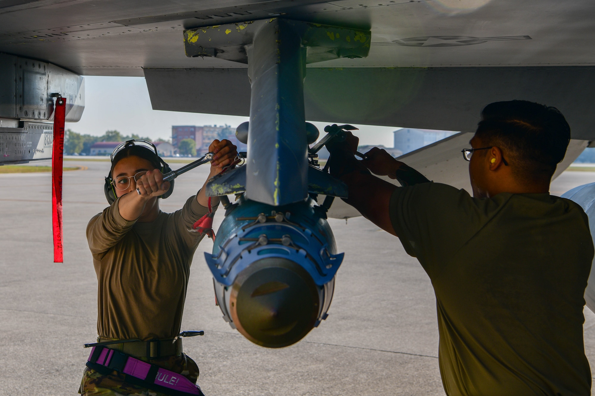 Airman 1st Class Addison Jones, 510th Fighter Generation Squadron weapons load crew member, left, and U.S. Air Force Staff Sgt. Brandon Sagaysay, 510th FGS weapons load crew chief, secure an inert munition onto an F-16 Fighting Falcon during the 3rd quarter Rapid Aircraft Generation and Employment (RAGE) event at Aviano Air Base, Italy, Oct. 14, 2022. The weapons load crews competed head-to-head and were tasked to load an F-16 with an inert guided bomb unit-31v3 Joint Direct Attack Munition (JDAM), a MK-84 Low Drag and one AIM-9L/M Sidewinder in the shortest possible amount of time. (U.S. Air Force photo by Senior Airman Brooke Moeder)