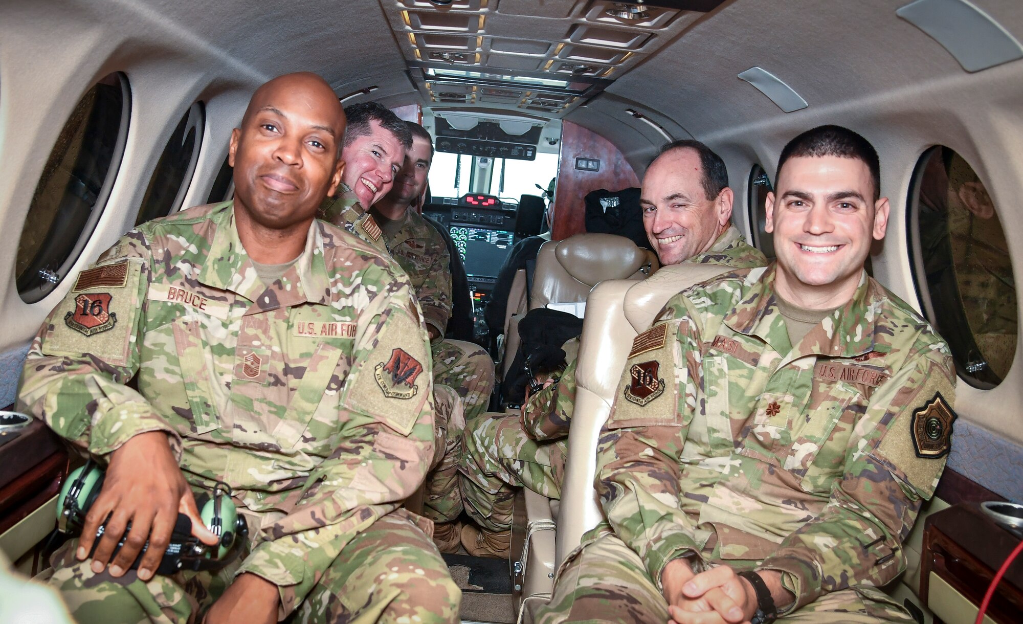 Individuals sit on aircraft and smile.