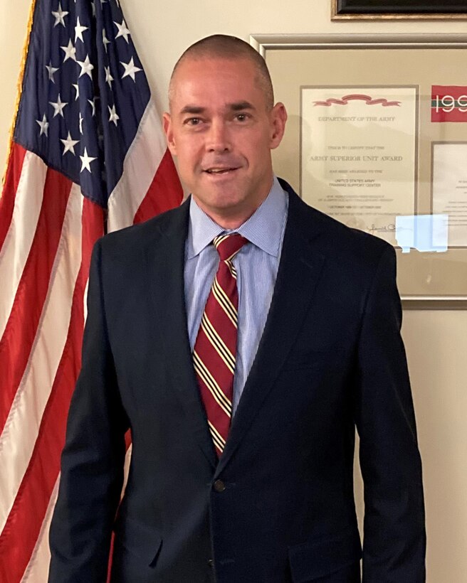 A man stands in front of a flag.