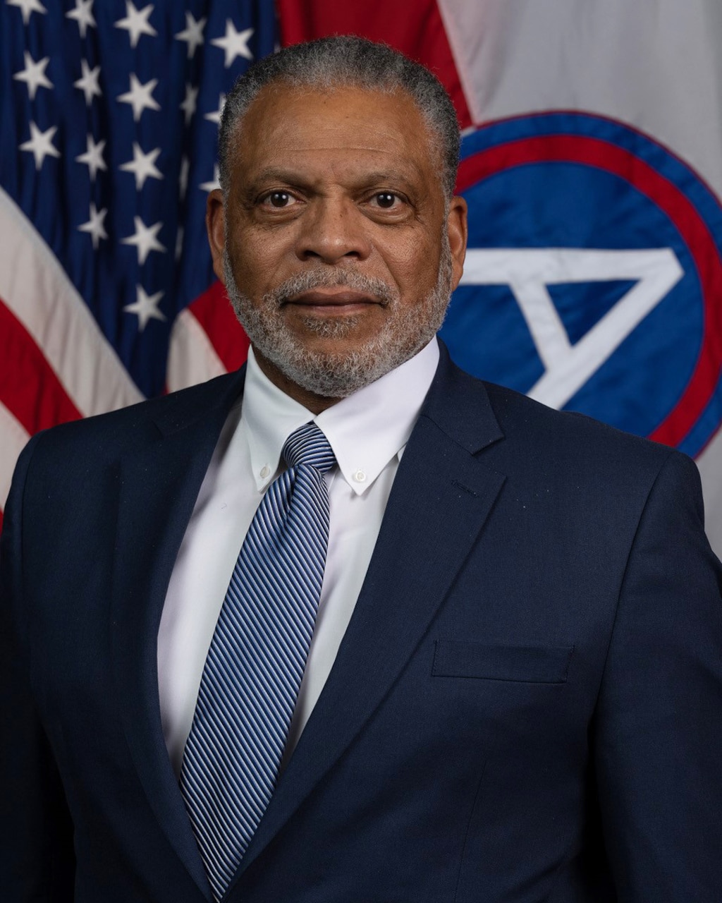 A man stands in front of a flag.