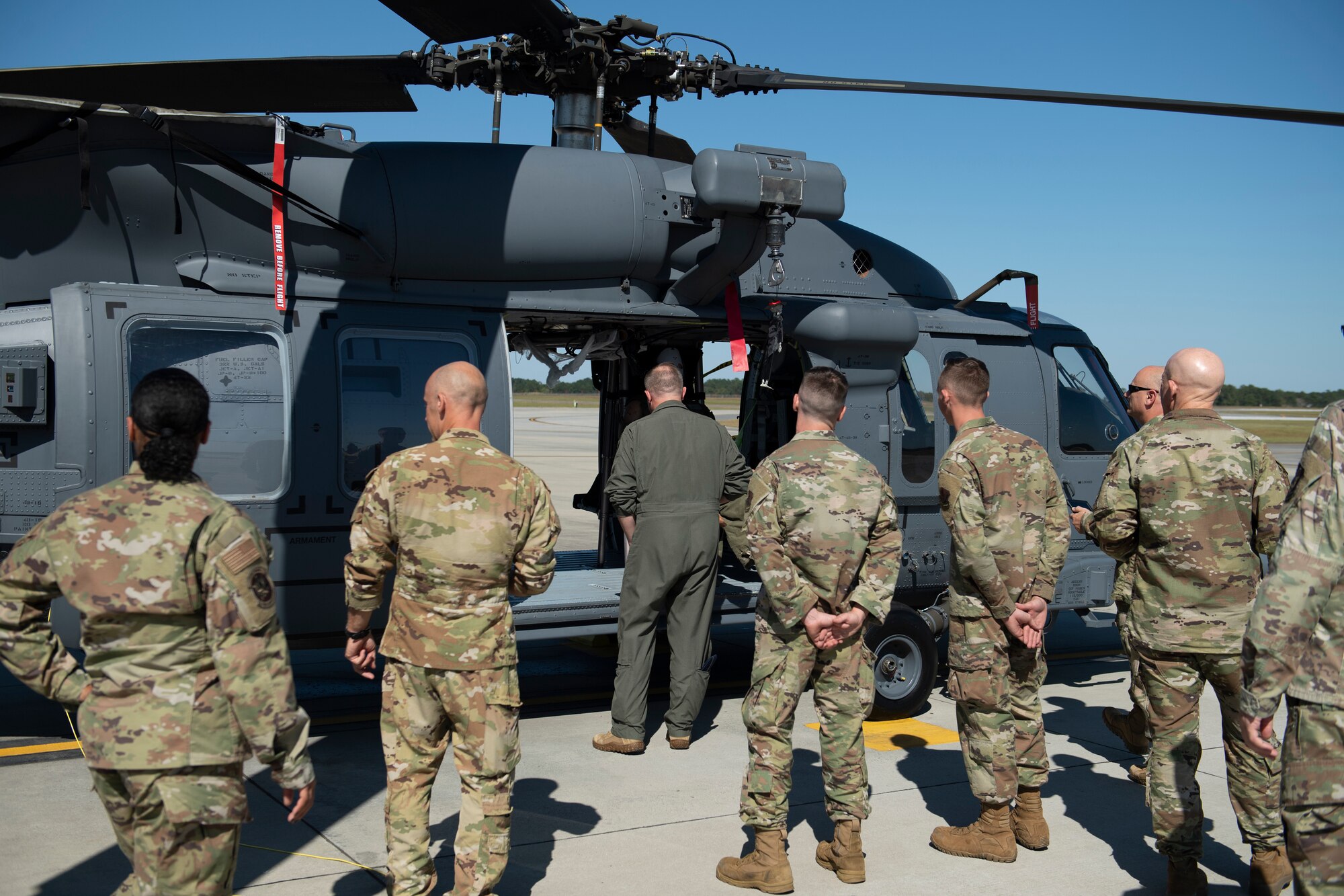 A photo of a group of men standing beside and looking at an HH-60W.