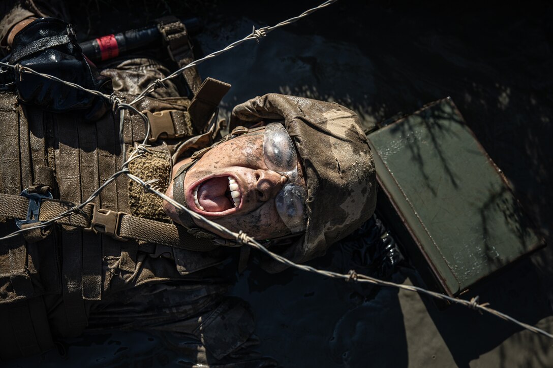 A U.S. Marine Corps recruit with Delta Company, 1st Recruit Training Battalion, crawls under barbed wire during the Crucible at Camp Pendleton, California, Oct. 17, 2022. The Crucible is a 54-hour culminating event consisting of mentally and physically demanding challenges with limited food and sleep. (U.S. Marine Corps photo by Cpl. Pio)