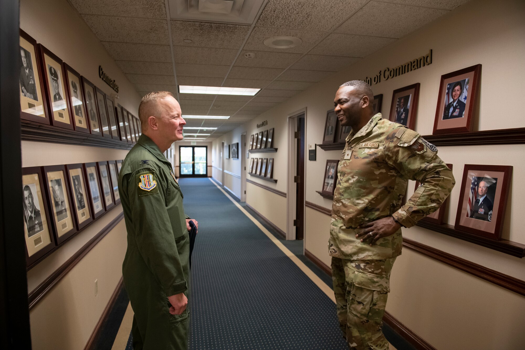 Two Airmen shown speaking in a hallway of a building. U.S. Air Force Brig. Gen. Alfred K. Flowers, Jr., right, speaks with Col. Derek Salmi, 60th Air Mobility Wing commander, in a long hallway at Travis Air Force Base, California, Oct. 12, 2022.