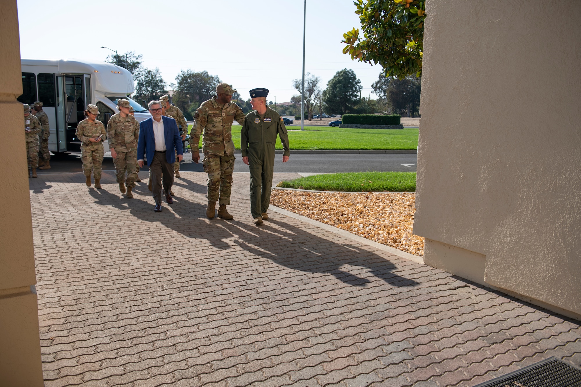 A group of Airmen and a civilian walk towards the entrance of a building at Travis Air Force Base, California, Oct. 12, 2022.
