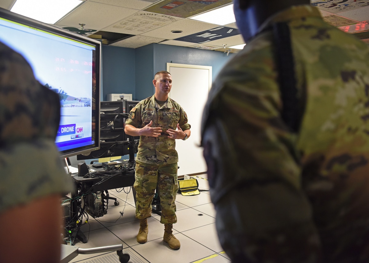 U.S. Air Force Master Sgt. Anthony Madrid, 316th Training Squadron flight chief for the signals intelligence flight, explains the impact a media news report could provide for intelligence collecting during the capstone exercise, Operation Loneshark, at Goodfellow Air Force Base, Texas, Oct. 11, 2022. Madrid played the news report to bring current information into the classroom, educating the students with more relevant content. (U.S. Air Force photo by Senior Airman Abbey Rieves)