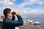 221018-N-RC359-1063 MANILA BAY (Oct. 18, 2022) Intelligence Specialist 3rd Class Emilio Gaytan, from Nashville, Tennessee, scans the horizon on vulture’s row as the U.S. Navy’s only forward-deployed aircraft carrier, USS Ronald Reagan (CVN 76), departs Manila Bay, Philippines, Oct. 18. Ronald Reagan, the flagship of Carrier Strike Group 5, provides a combat-ready force that protects and defends the United States, and supports alliances, partnerships and collective maritime interests in the Indo-Pacific region. (U.S. Navy photo by Mass Communication Specialist 3rd Class George Cardenas)