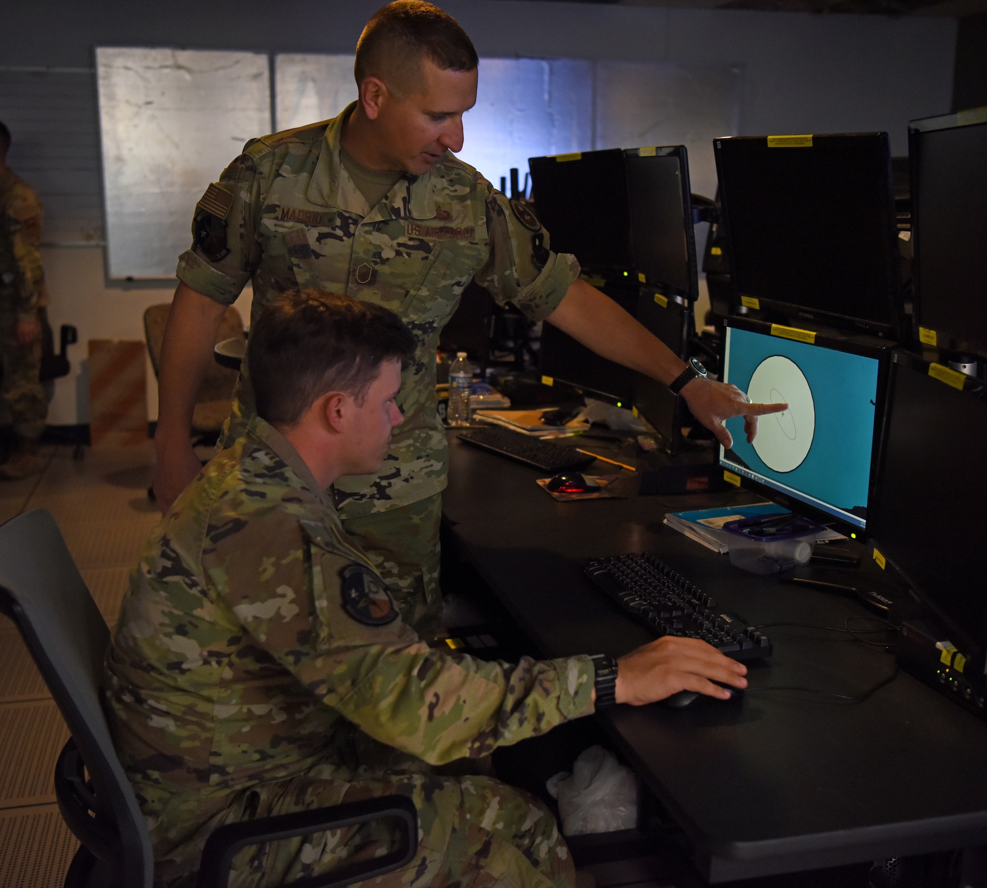 U.S. Air Force Master Sgt. Anthony Madrid, 316th Training Squadron signals intelligence flight chief, teaches Airman 1st Class Owen Arthur, 316th TRS student, how to read a signal hit during the student’s training capstone, Operation Loneshark, at Goodfellow Air Force Base, Texas, Oct. 11, 2022. The intelligence program identifies the radar emitting and its location.  It’s then up to the student to determine if the RADAR is a threat and its threat range. (U.S. Air Force photo by Senior Airman Abbey Rieves)