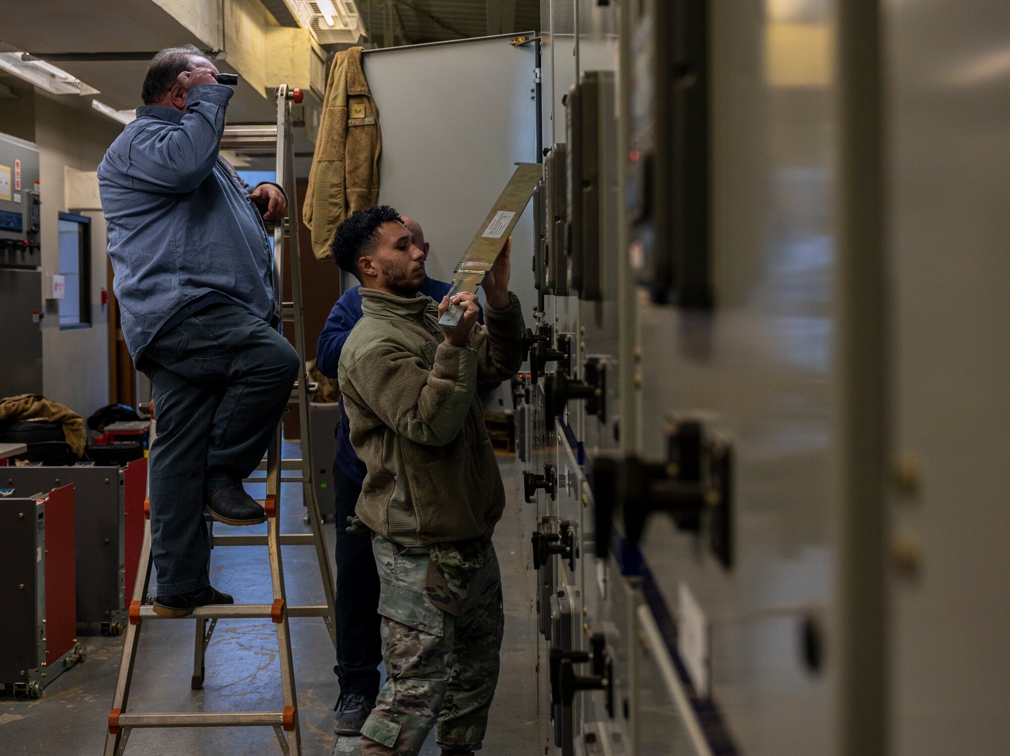 U.S. Air Force Senior Airman Darren Woodson, 51st Civil Engineer Squadron electrical systems journeyman assists the U.S. Air Force Civil Engineer Maintenance, Inspection and Repair Team (CEMIRT) members as they inspect high-voltage circuit breakers at Osan Air Base, Republic of Korea, Oct. 10, 2022.