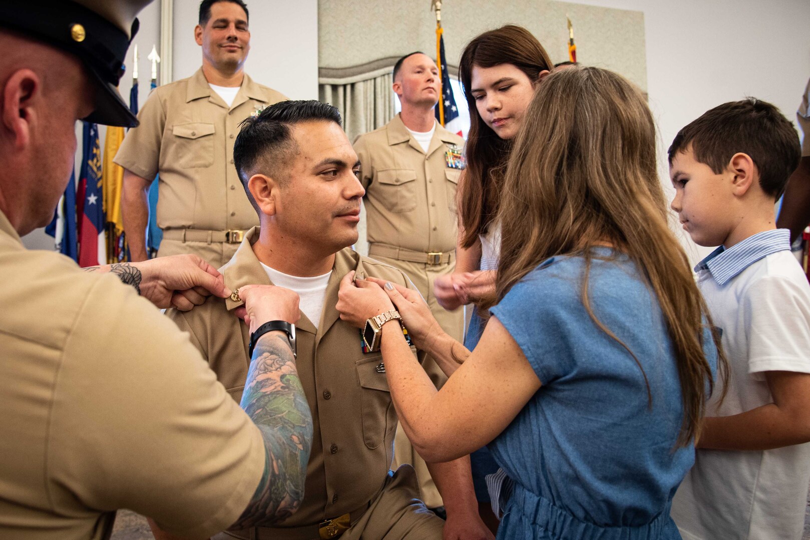 Chief Petty Officer Mike Arebalo receives his new rank from his mentor Chief Petty Officer Paul Bingham, left, and his family during his promotion ceremony.  Arebalo and four other sailors advanced to the rank of “Chief” during the ceremony held Friday, October 21, 2022, aboard Marine Corps Air Station Cherry Point.