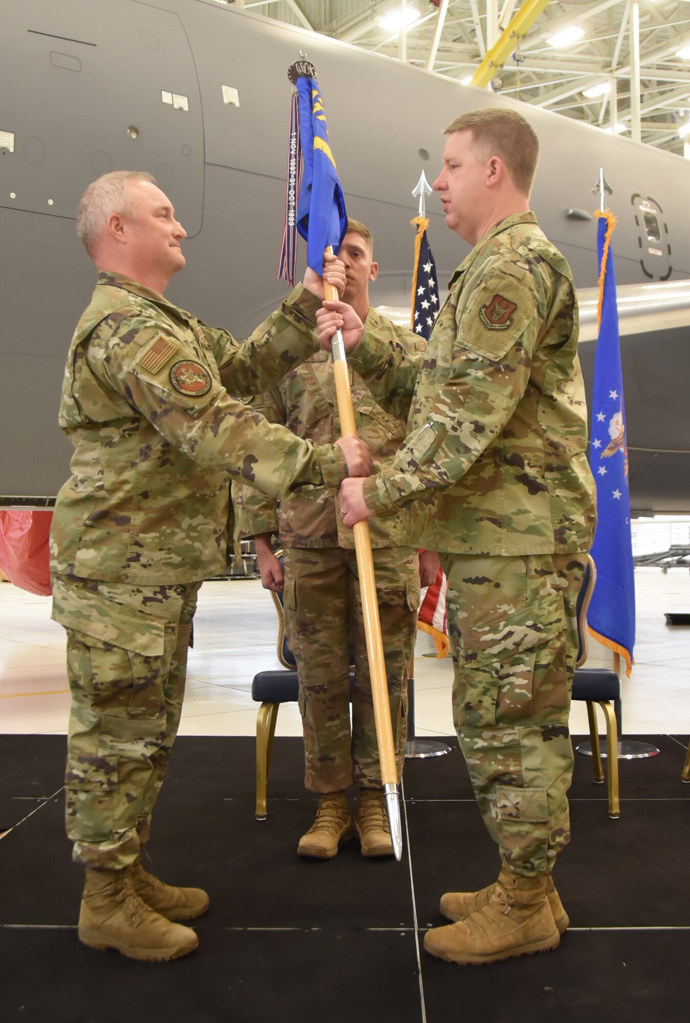 Left and right. Col. Mark Basler hands the guidon to Lt. Col. Scott Eklund while standing on podium.