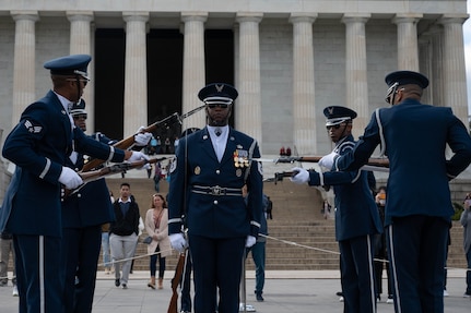 U.S. Air Force Senior Master Sgt. Antonio Lofton stands at attention while U.S. Air Force Honor Guard Drill Team members test his concentration during a 4-Member Drill during the Joint Services Drill Exhibition at the Lincoln Memorial Plaza, Washington, D.C., Oct. 19, 2022. The event marked the first “Drill Off” in ten years. (U.S. Air Force photo by Kristen Wong)