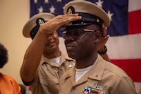 NAVAL STATION NORFOLK (Oct. 21, 2022) A chief petty officer mentor covers Chief Logistics Specialist Kokou Moutchou during the Naval Surface Force Atlantic chief petty officer pinning ceremony onboard Naval Station Norfolk, Oct. 21, 2022. Nine Sailors received their gold-fouled anchors during the ceremony. (U.S. Navy photo by Mass Communication Specialist 1st Class Jacob Milham)