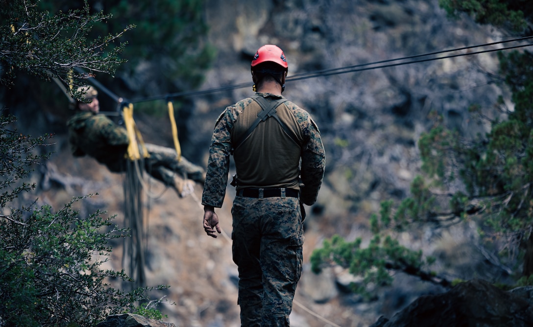 U.S. Marine Corps Sgt. Jovanny Duran, a mountain warfare instructor with Marine Corps Mountain Warfare Training Center (MCMWTC), Marine Air Ground Task Force Training Command, assists a Marine with 2nd Battalion, 1st Marine Regiment, 1st Marine Division, on the one-rope bridge during Mountain Exercise (MTX) 1-23 at MCMWTC, Bridgeport, California, Sept. 19, 2022. MTX is a month-long exercise designed to prepare units to survive and operate effectively in austere, mountainous terrain. (U.S. Marine Corps photo by Cpl. Shane T. Beaubien)