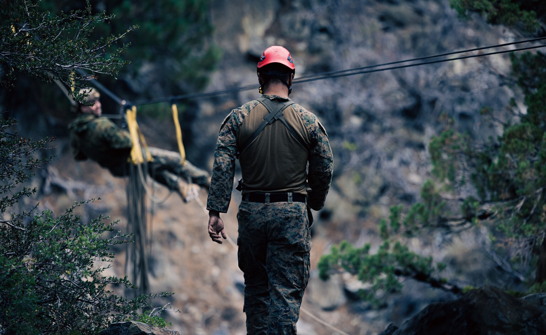 A US Marine instructor assists a Marine on the on-rope bridge