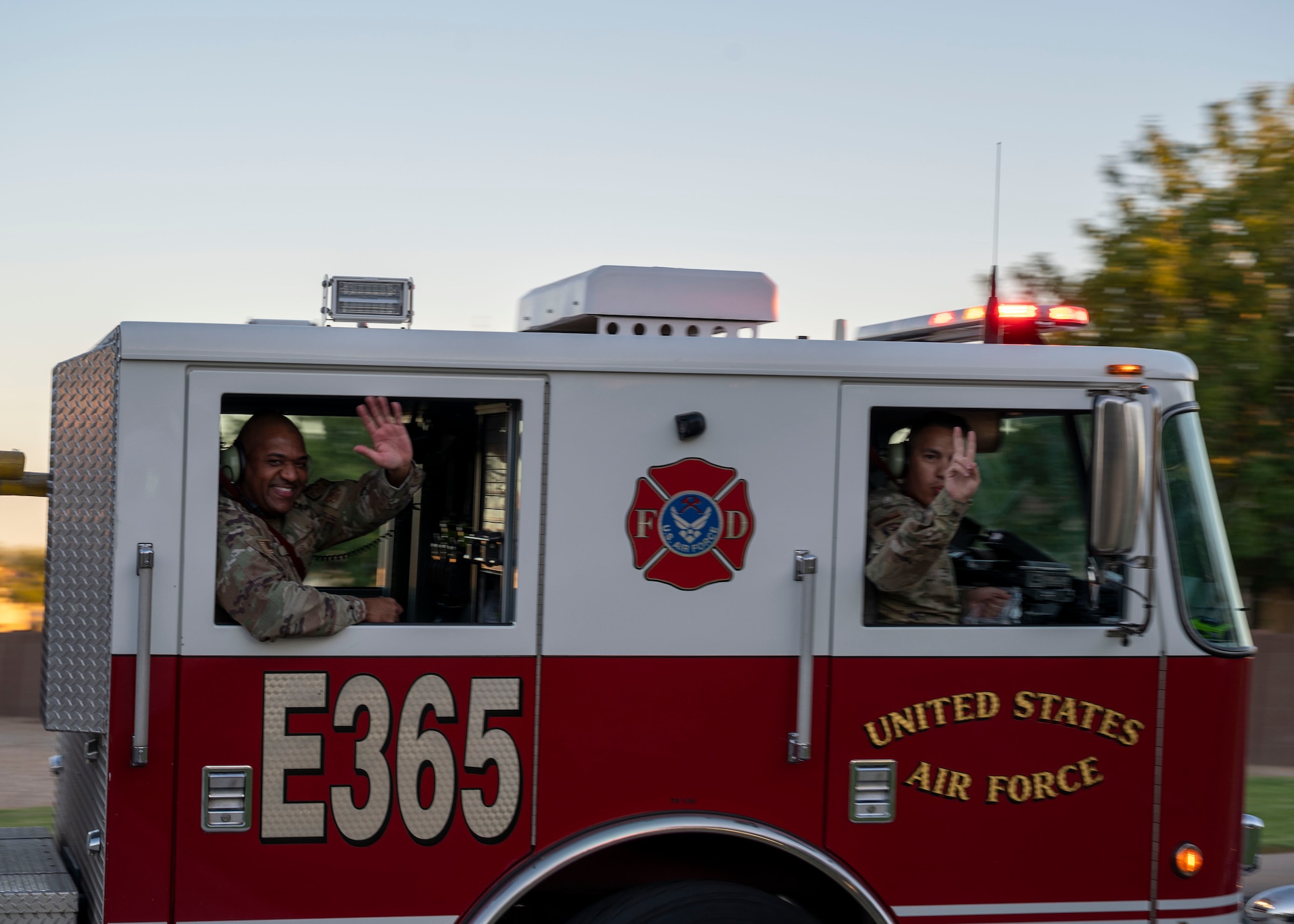 U.S. Air Force Airmen assigned to the 56th Civil Engineer Squadron Fire Department wave as they pass through base housing Oct. 13, 2022, at Luke Air Force Base, Arizona.