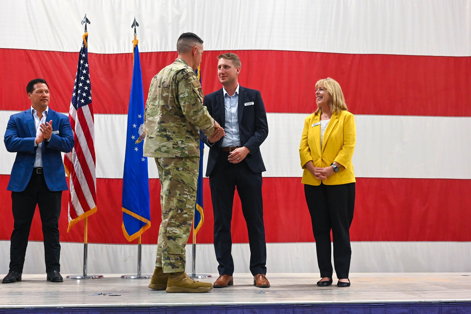 U.S. Air Force Chief Master Sgt. Jason Shaffer, 56th Fighter Wing command chief, coins Thomas Maynard and Jenni Thomas, honorary commander inductees, during a ceremony, Oct. 14, 2022, at Luke Air Force Base, Arizona.