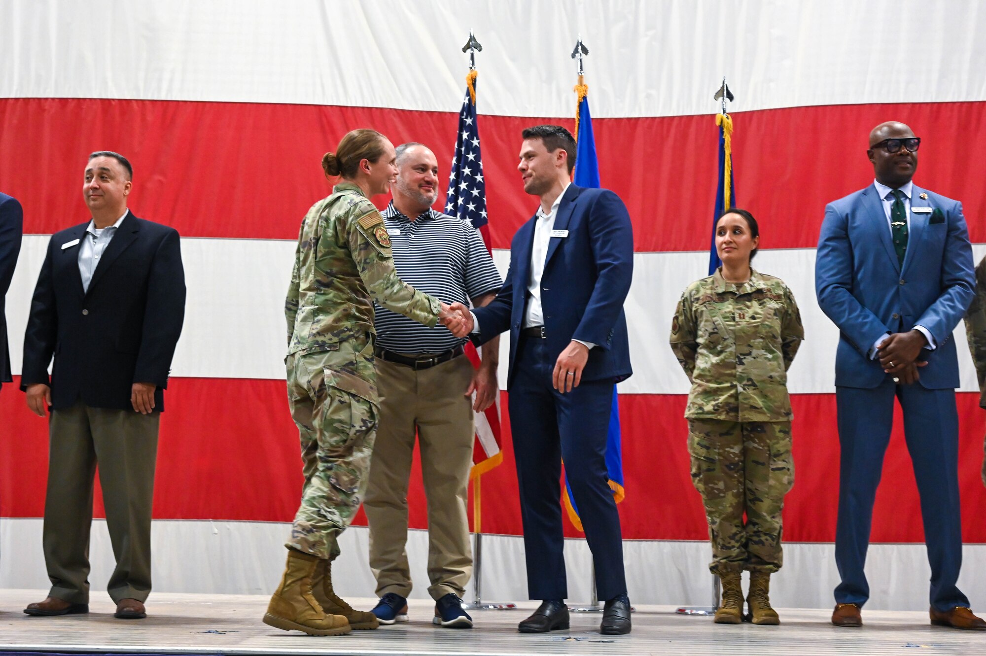U.S. Air Force Lt. Col. Kristen Schnell, 56th Comptroller Squadron commander, coins Gabe Hill and Kevin Michalzuk, honorary commander inductees, during a ceremony, Oct. 14, 2022, at Luke Air Force Base, Arizona.