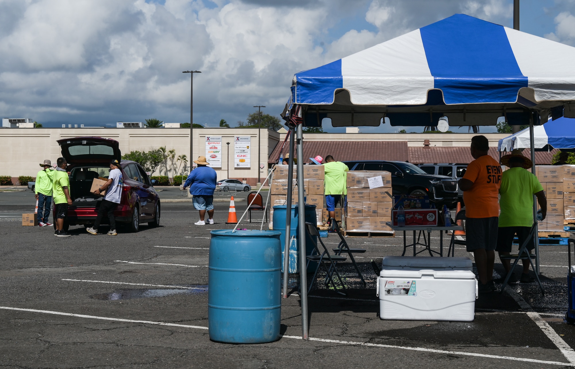Morale, Welfare, and Recreation volunteers and Airmen provide water to military housing residents on Joint Base Pearl Harbor-Hickam, Hawaii, Oct. 21, 2022. Due to a water line break on October 14, 2022, water distribution sites were postured at the Navy Exchange and Hickam Exchange parking lots to provide affected military housing residents with potable water. (U.S. Air Force photo by Staff Sgt. Alan Ricker)