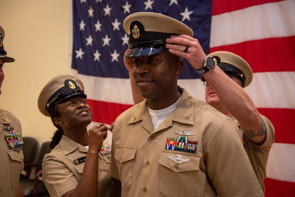 NAVAL STATION NORFOLK (Oct. 21, 2022) Mentors cover Chief Hospital Corpsman Rashad Mckenzie during the Naval Surface Force Atlantic chief petty officer pinning ceremony onboard Naval Station Norfolk, Oct. 21, 2022. Nine Sailors received their gold-fouled anchors during the ceremony. (U.S. Navy photo by Mass Communication Specialist 1st Class Jacob Milham)
