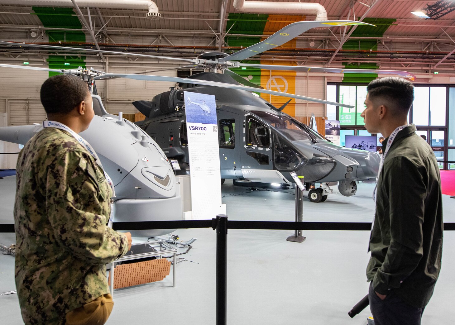 Aviation Ordnanceman 1st Class Kayla Reed-Blake, assigned to Strike Fighter Squadron (VFA) 86, left, and Aviation Ordnanceman 1st Class Nick Olguin, assigned to USS George H.W. Bush (CVN 77), interact with a display model during the World Naval Defence Exhibition (EURONAVAL) Trade Show in Paris, Oct. 18, 2022.