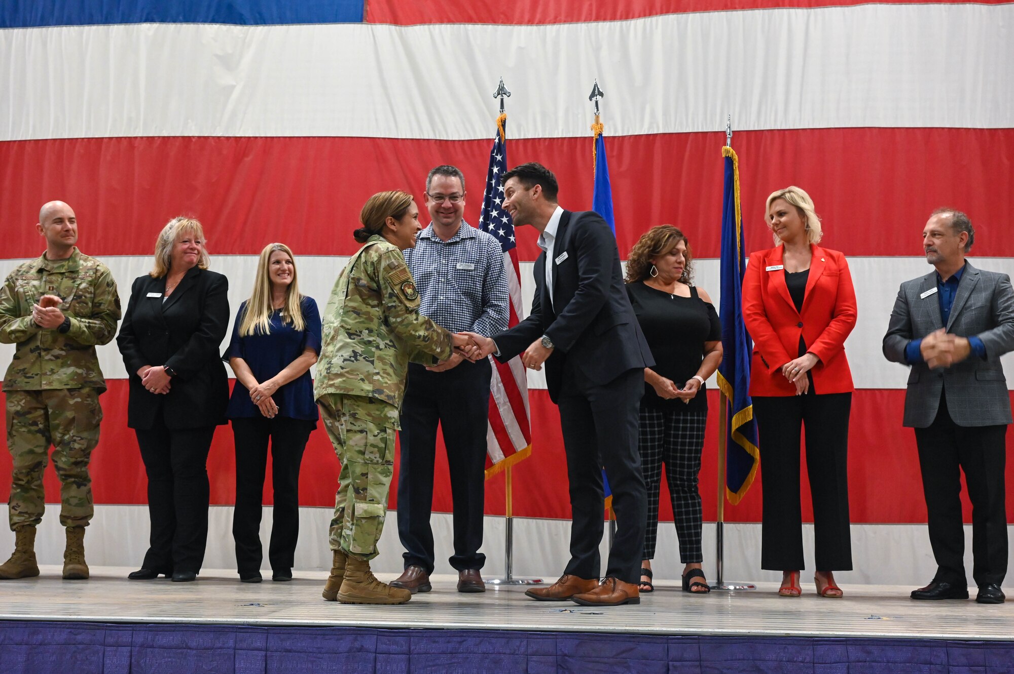 U.S. Air Force Maj. Fany E. Colon De Hays, 56th Force Support Squadron commander, coins Chris Calcaterra and Alex Tsakaris, honorary commander inductees, during a ceremony, Oct. 14, 2022, at Luke Air Force Base, Arizona.