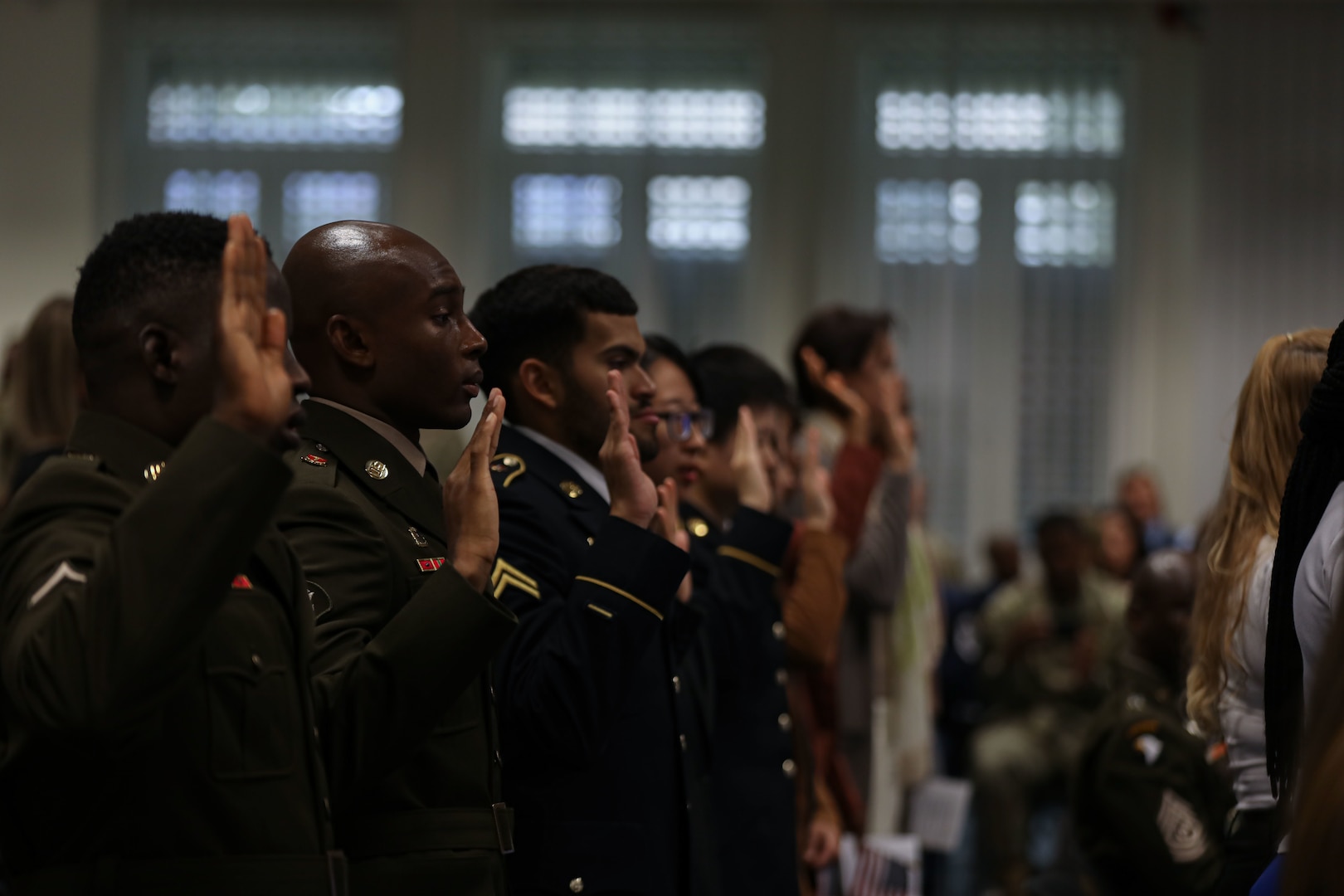 Soldiers in uniform stand at attention with their right hand raised.