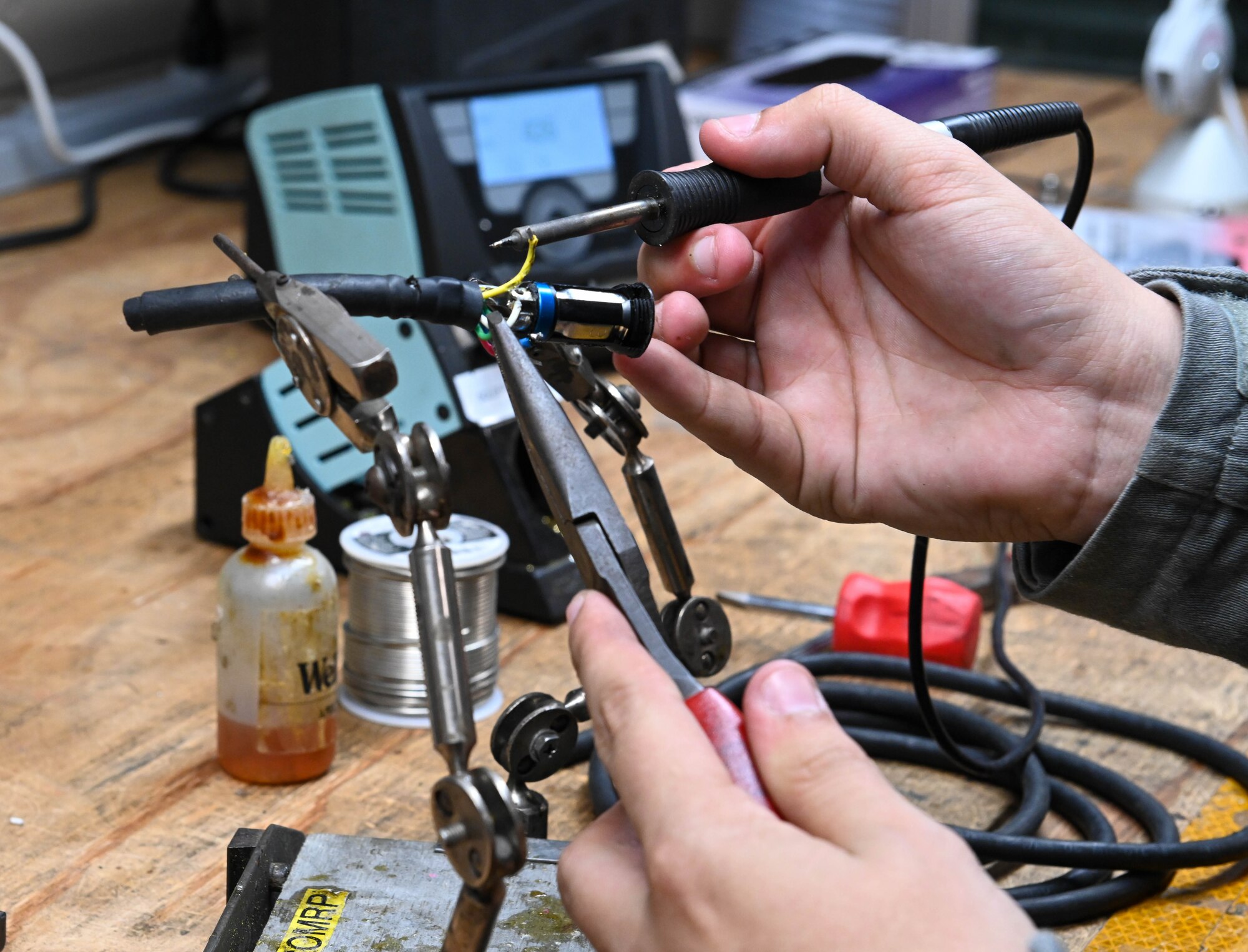 U.S. Air Force Senior Airman Mark Friesel, 509th Sortie Support section, composite tool kit technician repairs aircraft ground communication cords at Whiteman Air Force Base, Missouri, October 12, 2022. The soldering iron solders the wire to the connector. (U.S. Air Force photo by Airman 1st Class Hailey Farrell)