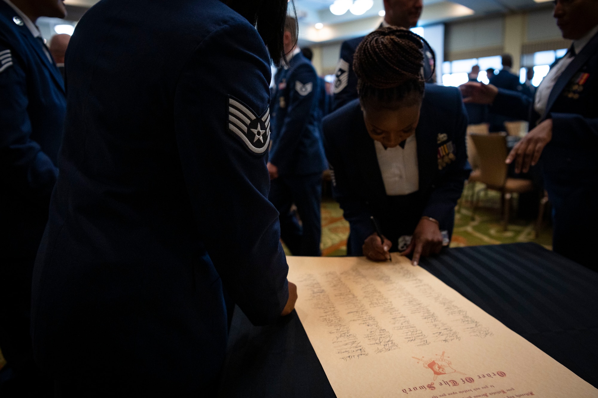 U.S. Air Force Airmen attending an Order of the Sword ceremony for retired Lt. Gen. Marshall B. Webb, former AFSOC commander and AETC commander, sign a scroll at Keesler Air Force Base, Mississippi, Oct. 15, 2022.