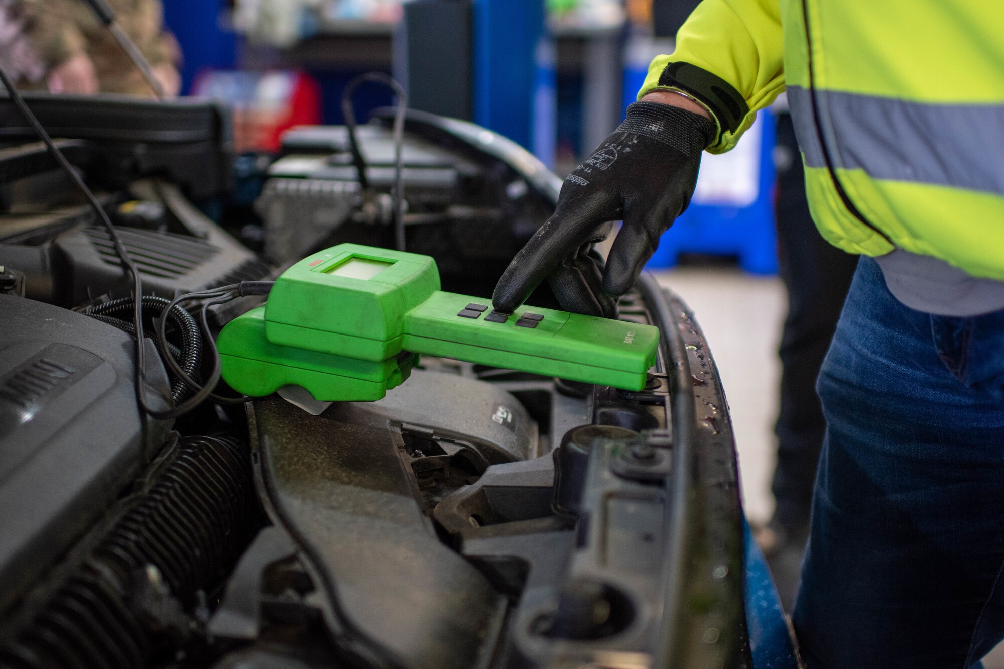 A vehicle safety representative uses a battery tester on a car.