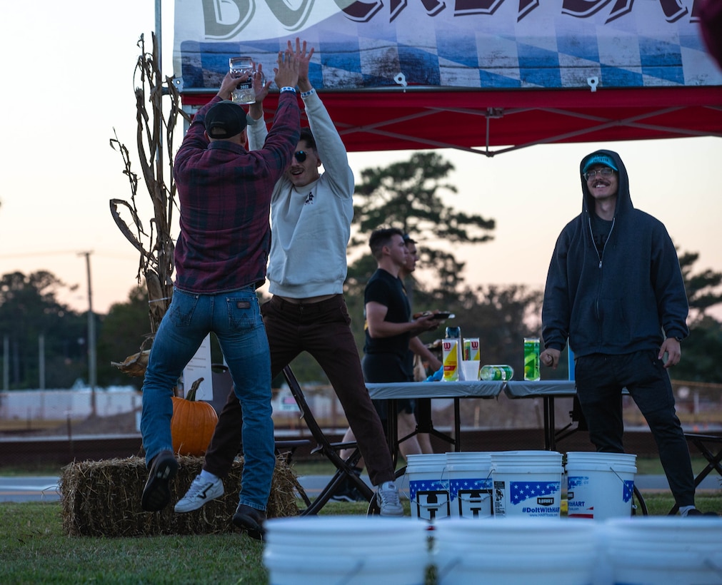 U.S. Marine Corps Cpl. Vaugh Graber (left), a network administrator with Marine Air Control Group, and Cpl. Trevor Krugman (right), a satellite communications operator, celebrate with a high-five after winning a bucket pong game during Rocktoberfest, Marine Corps Air Station Cherry Point, North Carolina, Oct. 20, 2022. Marine Corps Community Services Cherry Point hosts Rocktoberfest annually. More than 1,000 service members and civilians gathered to participate in an array of games, listen to live music, and enjoy free food and drinks. (U.S. Marine Corps photo by Lance Cpl. Jade Farrington)