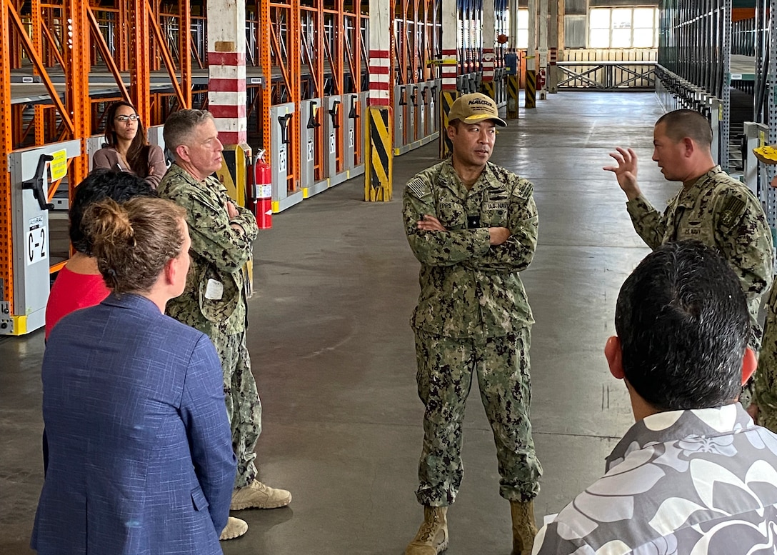 A group of people stand talking in a warehouse