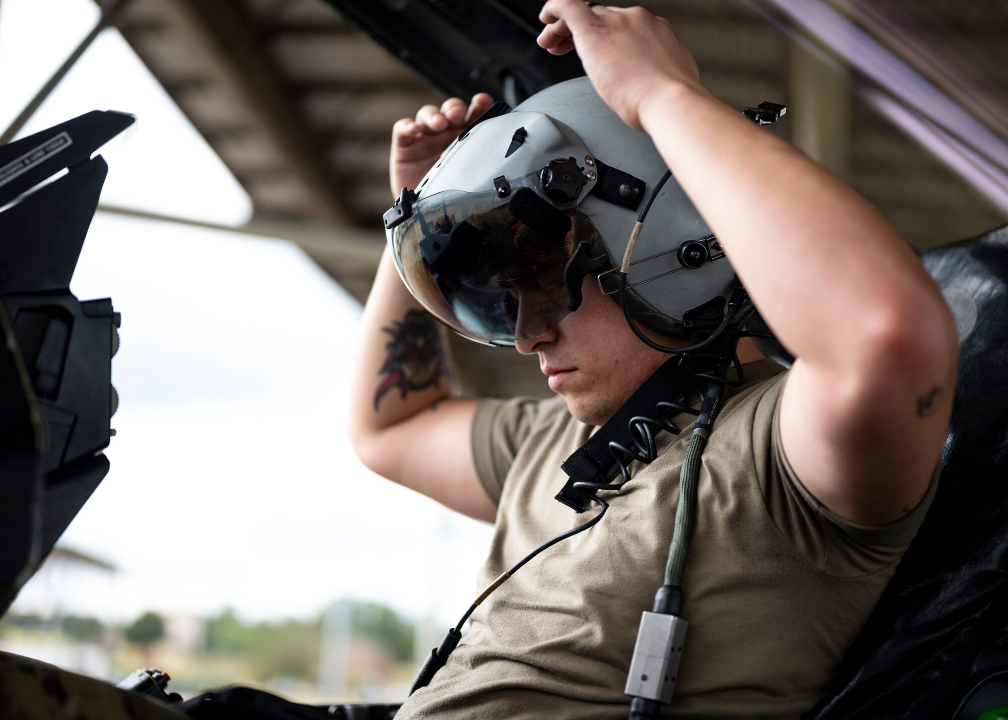 Airman puts on a flight helmet inside a F-16C Fighting Falcon