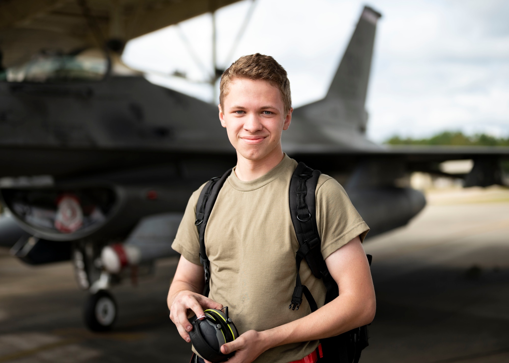 Airman stands in front of a F-16C Fighting Falcon