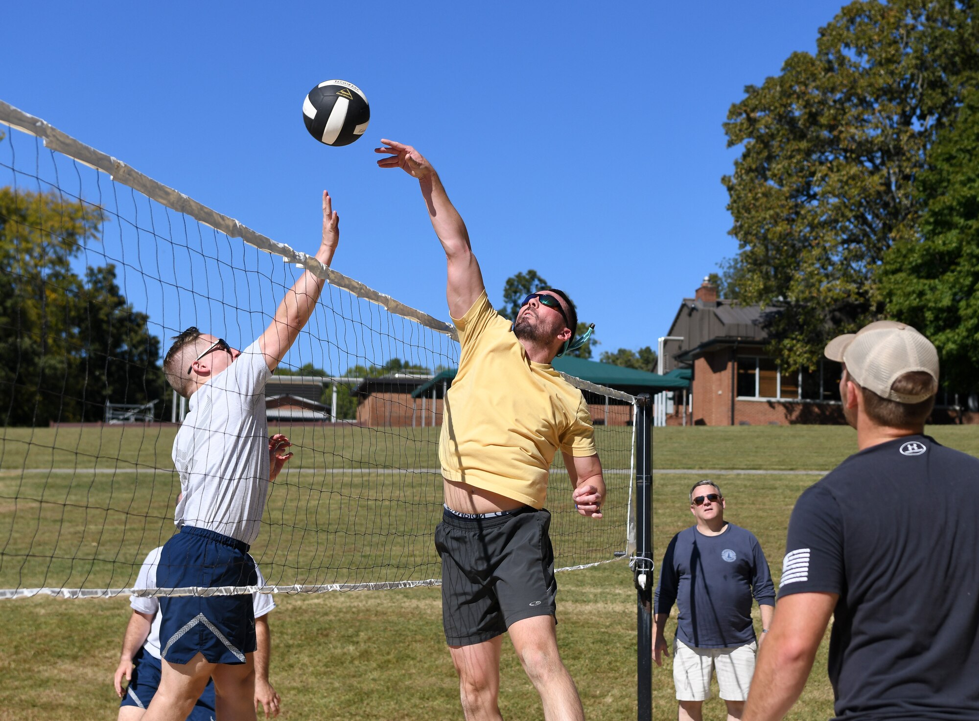 Two men trying to hit volleyball at the net