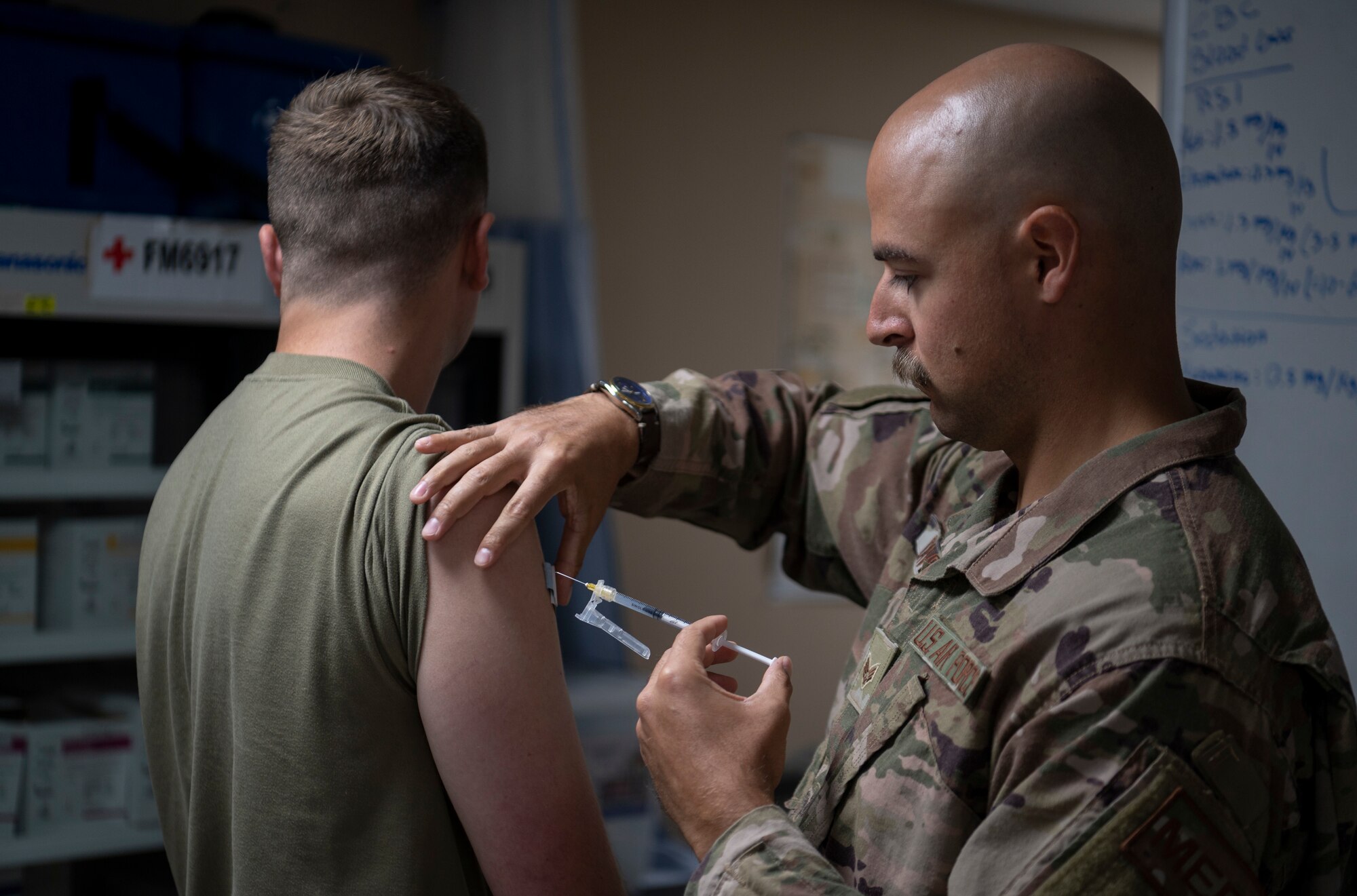 U.S. Air Force Senior Airman Caleb Beaver, 332d Expeditionary Medical Squadron, Emergency Medical Technician, delivers a COVID-19 booster to an Airman at an undisclosed location, Southwest Asia, Oct. 20, 2022. Immunization with the new COVID-19 booster vaccine provides improved protection against the Omicron variants of COVID-19. (U.S. Air Force photo by Tech. Sgt. Jeffery Foster)