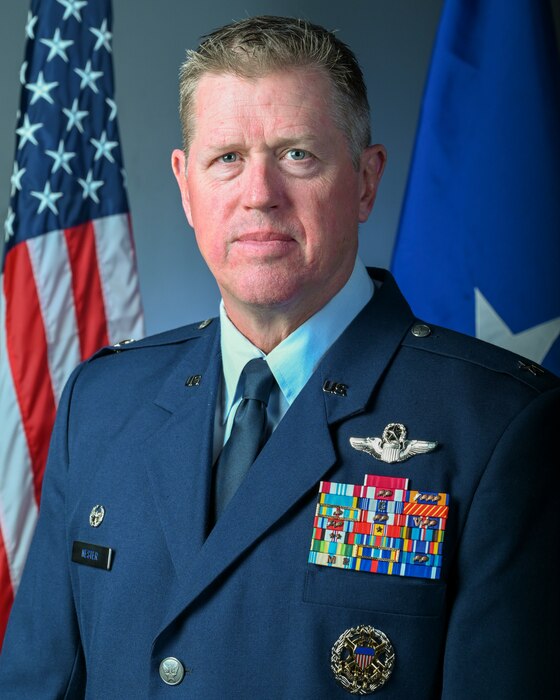 Brig. Gen. Stephen J. Nester poses in a blue dress uniform in front of an American flag on his right and a brigadier general flag on his left.