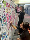 Alex Chestnut, chemist, and Sabrina Duncan, environmental engineer, color a Breast Cancer Awareness Month poster during a training break October 12, 2022. The poster, hung up in the hallway at Huntsville Center during the entire month of October, is one of many ways the Safety Office and breast cancer survivor Tara Payne are raising awareness about the importance of screenings and early detection. (Photo by Kristen Bergeson)