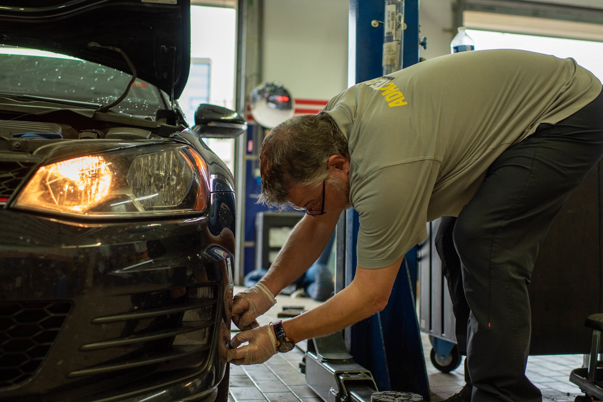 A man looks at a car's tire.