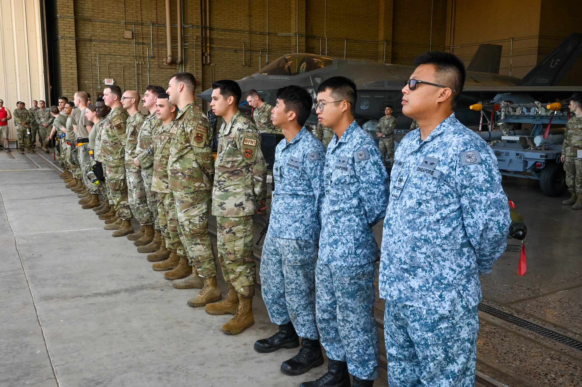 Airmen from the 56th Maintenance Group and Singaporean service members prepare for a quarterly weapons load competition, Oct. 7, 2022, at Luke Air Force Base, Arizona.