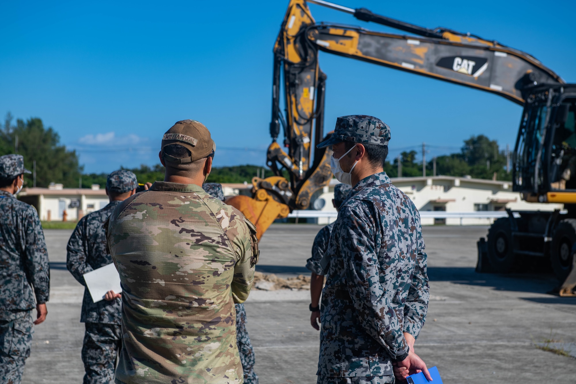 Airman and Japan Air Self-Defense Force member speak at a airfield damage repair simulation site.